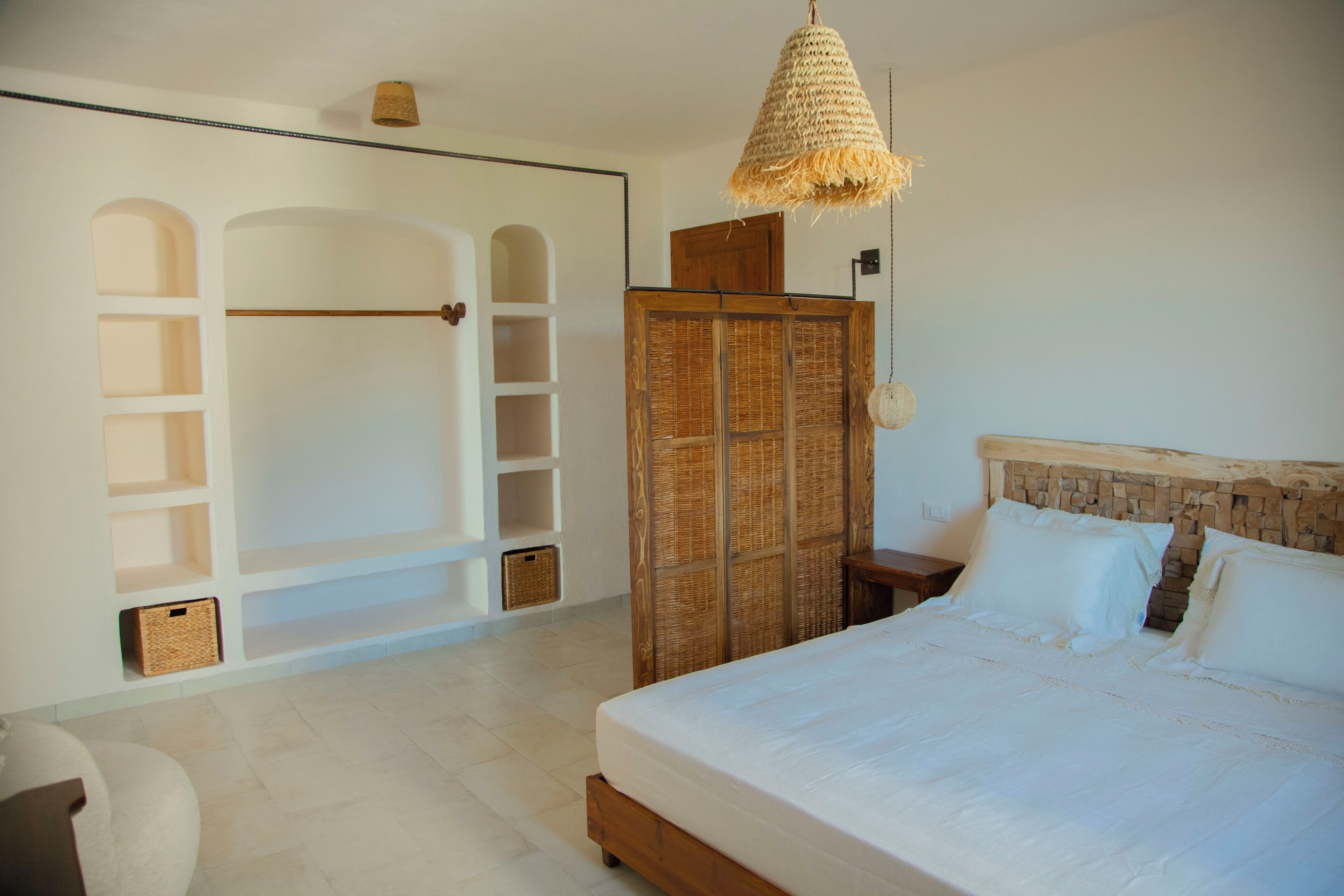 A bedroom with a large bed, a wardrobe, and built-in shelving.