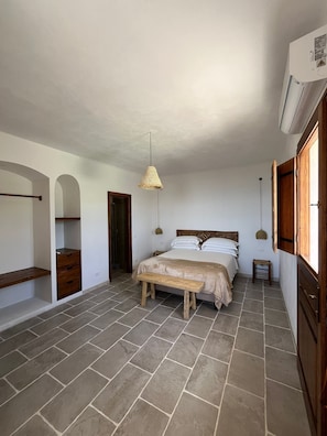 Ein Schlafzimmer mit einem Bett, einer Bank, einer Hängelampe und einer Klimaanlage.