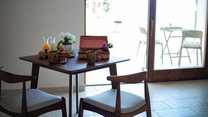 A dining table with chairs, a basket, a vase with flowers, and a window with a view of the outside. - Borgo Corbaro - Exclusive Retreat  (Forio)