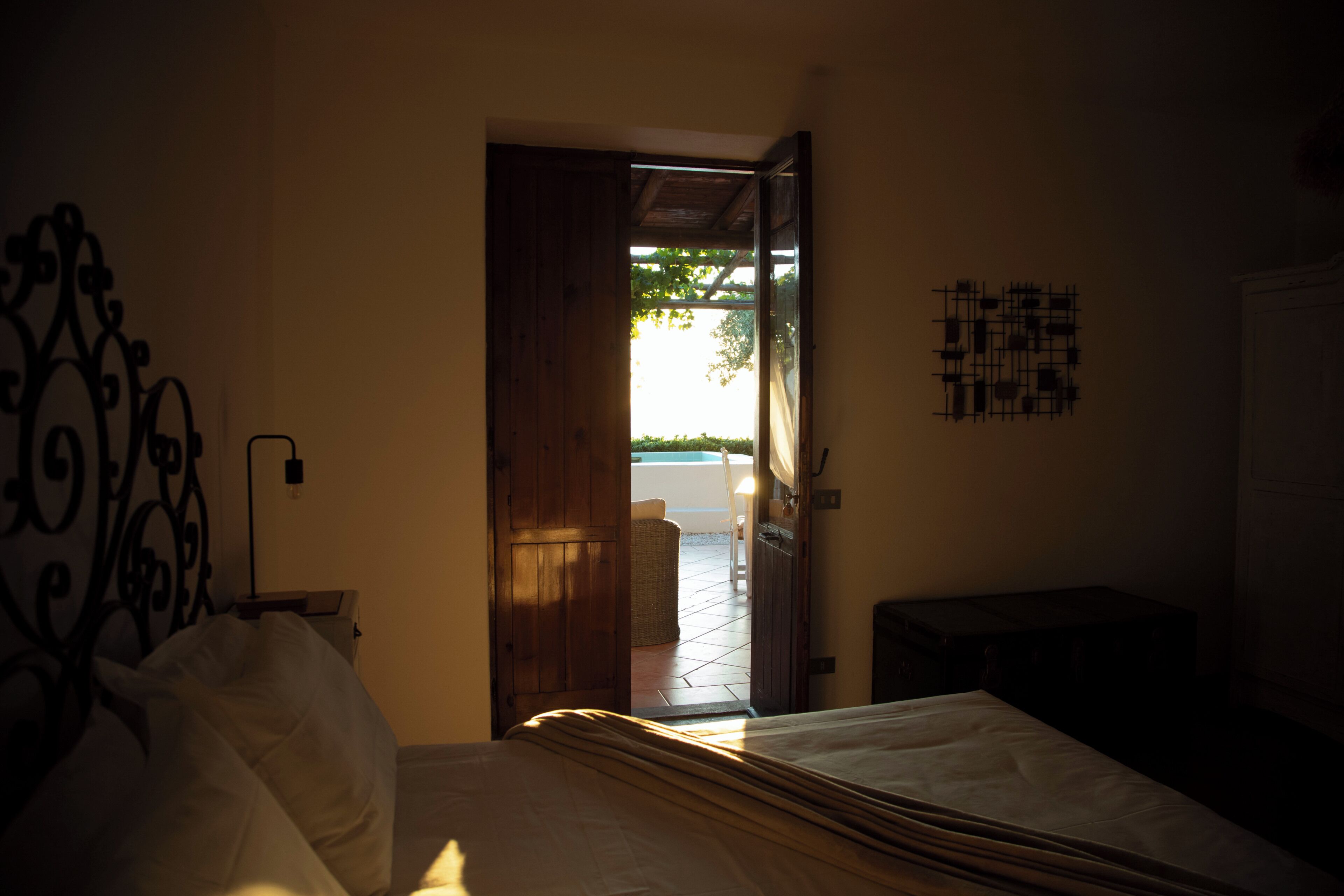 Un dormitorio con una cama, una puerta de madera que da a un espacio exterior y una obra de arte colgada en la pared.