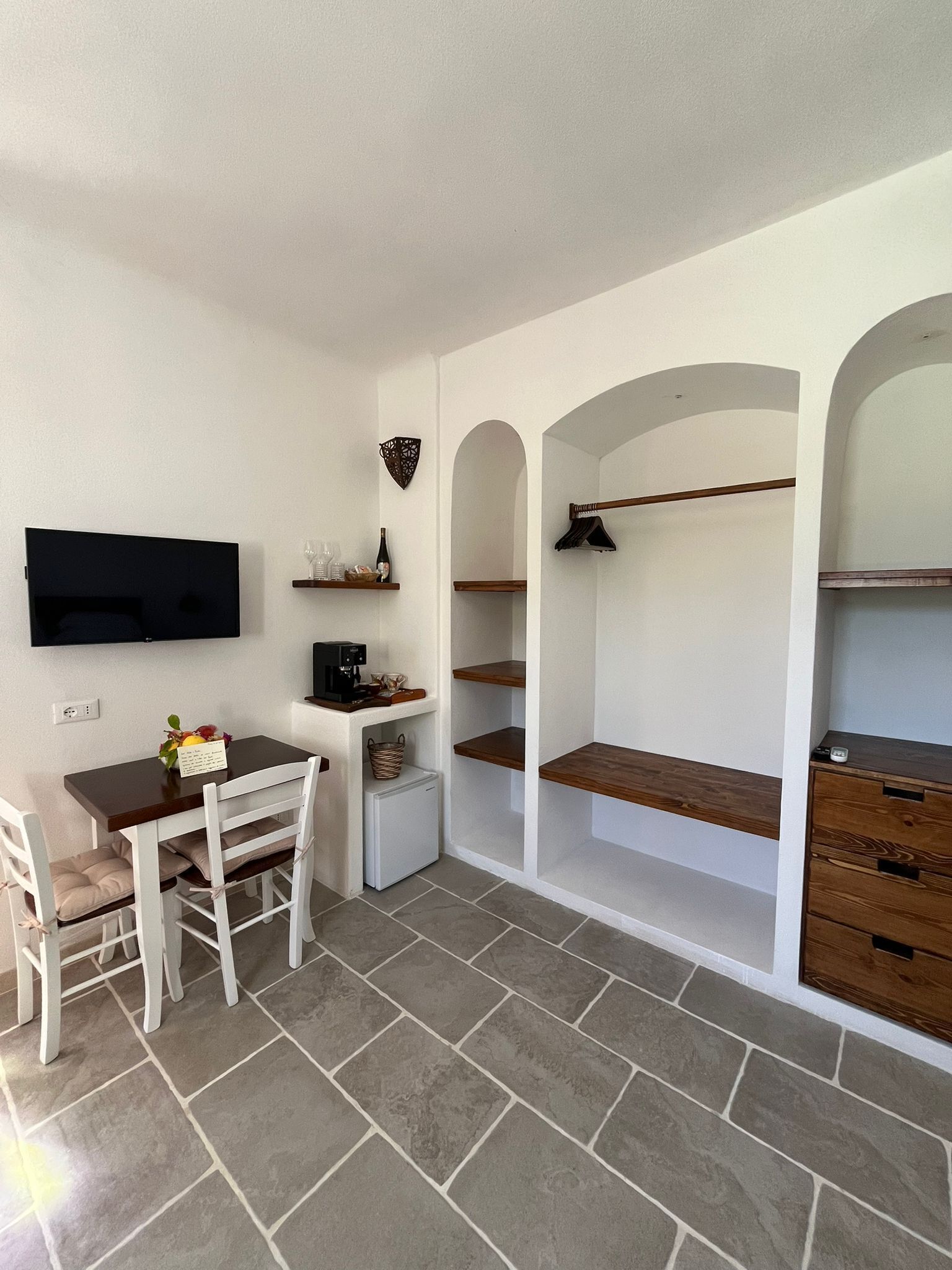 A compact room with a dining table, chairs, a TV, and built-in shelves.