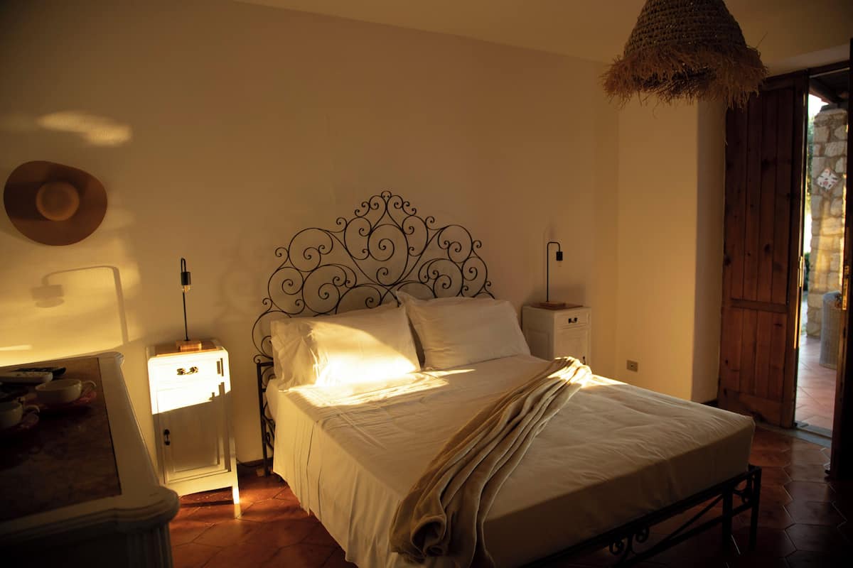 A bedroom with a bed, bedside tables, a lamp, a hat on the wall, and a door.