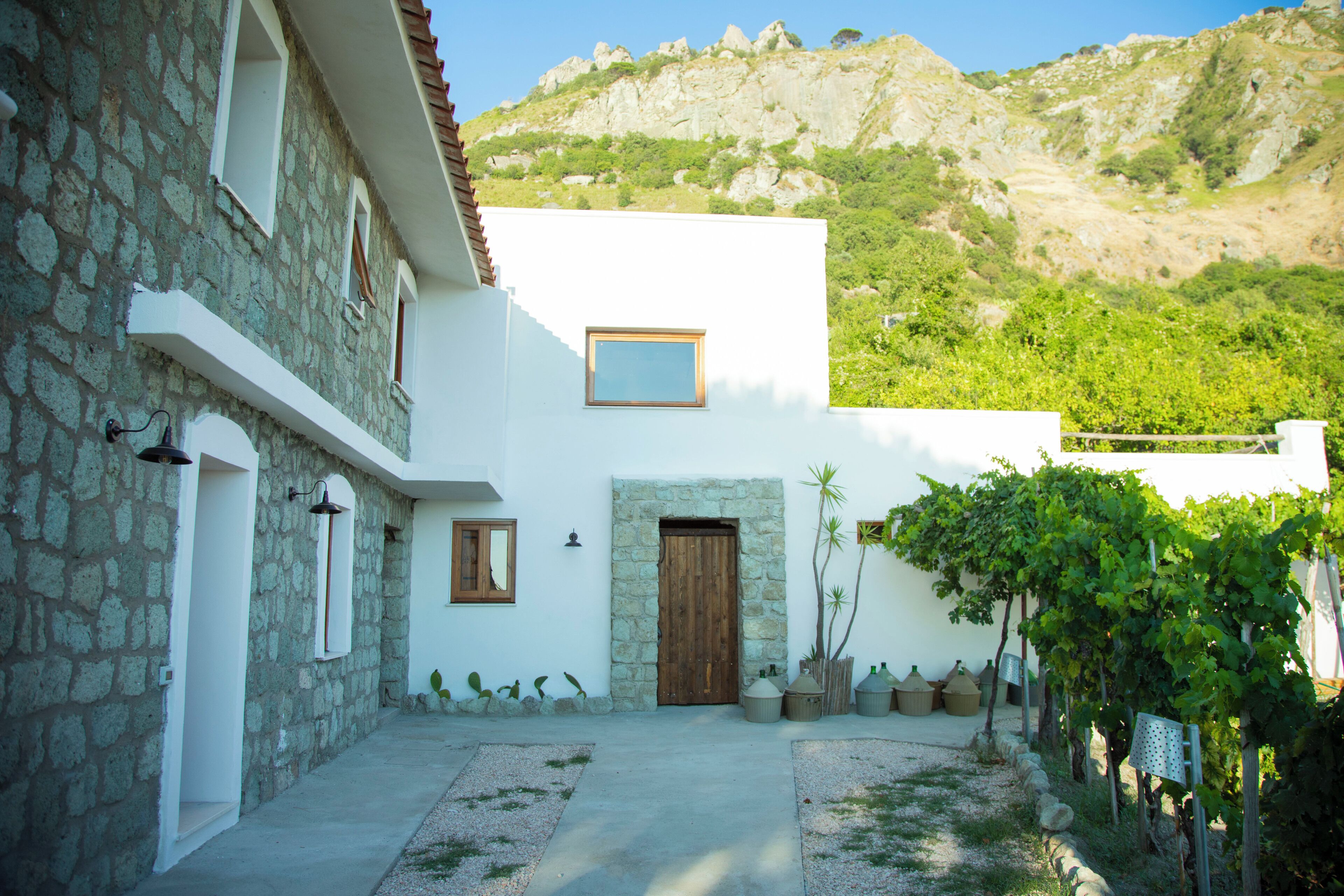 A stone building with a white facade, a wooden door, and a small window.