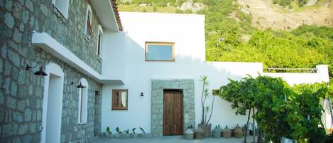 A stone building with a white facade, a wooden door, and a small window.