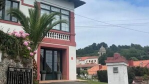 Ein zweistöckiges Gebäude mit Balkon, einem verschlossenen Eingang und einer kleinen weißen Struktur rechts.
