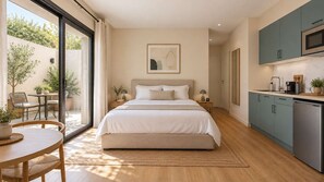 A bedroom with a large bed, a dining area with a table and chairs, a kitchen with cabinets and appliances, and a sliding glass door leading to an outdoor area. - Escapade à deux · Terrasse privée · Face à Charléty (Paris)