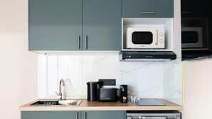 A kitchen with a built-in microwave, coffee maker, toaster, and a sink. - Appartement design avec Terasse et climatisation (Paris)