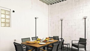 A dining area with a brick wall, a window with frosted glass, and a table set with breakfast. - Appartement design avec Terasse et climatisation (Paris)