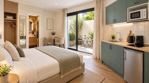 A modern bedroom with a large bed, a built-in wardrobe, a small dining area, and a kitchenette with a microwave. - Escapade à deux · Terrasse privée · Face à Charléty (Paris)