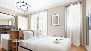 A hotel room with a bed, a chair, a desk, a mirror, a picture on the wall, and a window with curtains. - Prestige appartement à Paris (Paris)