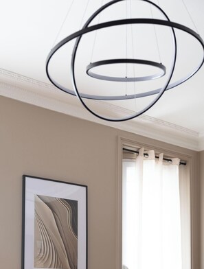 A modern interior with a circular light fixture, a framed abstract artwork, and a window with curtains.