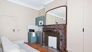 A compact room with a kitchenette, a fireplace, and a bed. - Prestige appartement à Paris (Paris)
