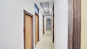 Un couloir avec des portes en bois, des murs blancs et un sol carrelé.