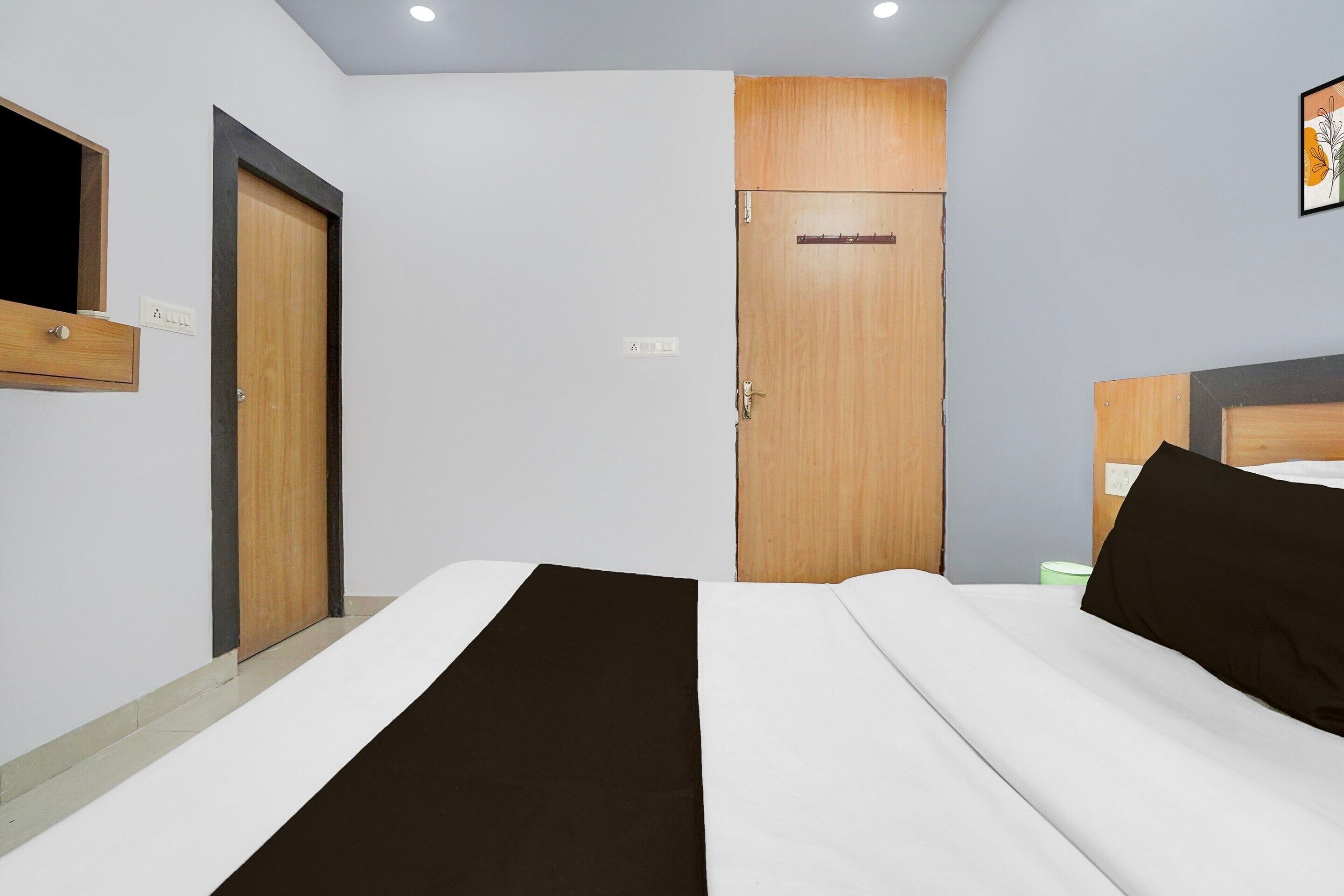 Habitación de hotel con cama, armario, espejo y una obra de arte colgada en la pared.
