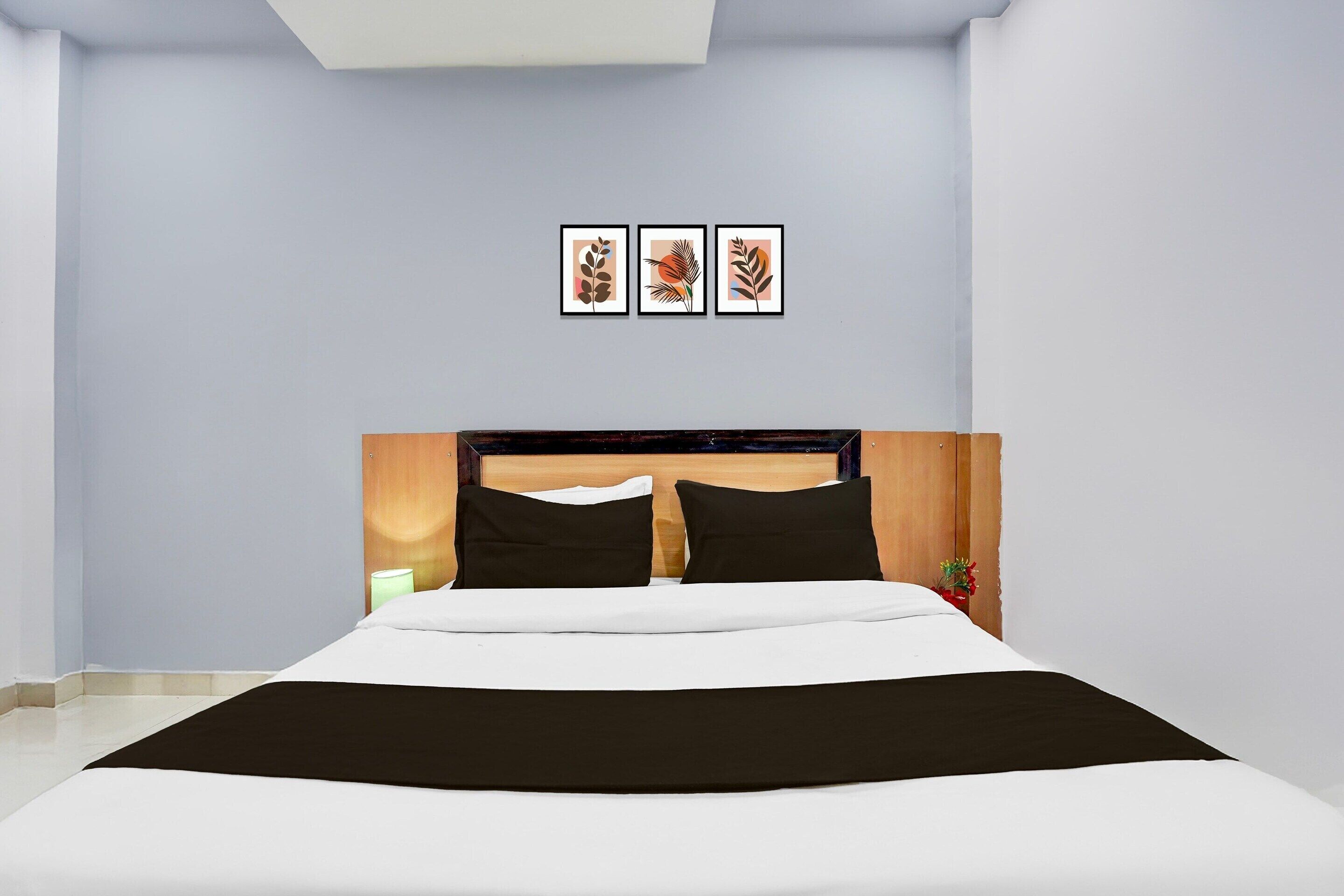 A bedroom with a bed, a headboard, and three framed pictures on the wall.