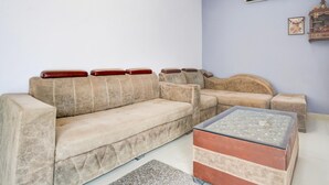 Un salon avec un canapé beige, une table basse en verre et un petit tapis.