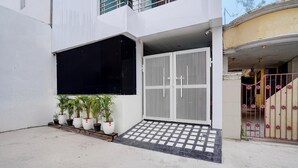A modern building with a gated entrance, potted plants, and a tiled entrance area. - Deluxe Neelam Hotel (Bareilly)
