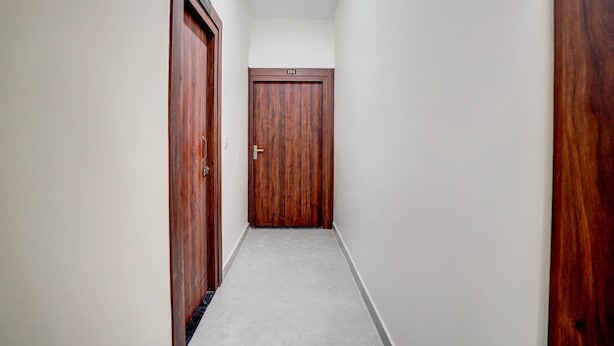 A narrow hallway with a wooden door at the end, a number '204' above it, and a carpeted floor. - Deluxe Neelam Hotel (Bareilly)