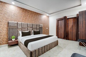 A modern bedroom with a large bed, a nightstand, a potted plant, and a wardrobe.