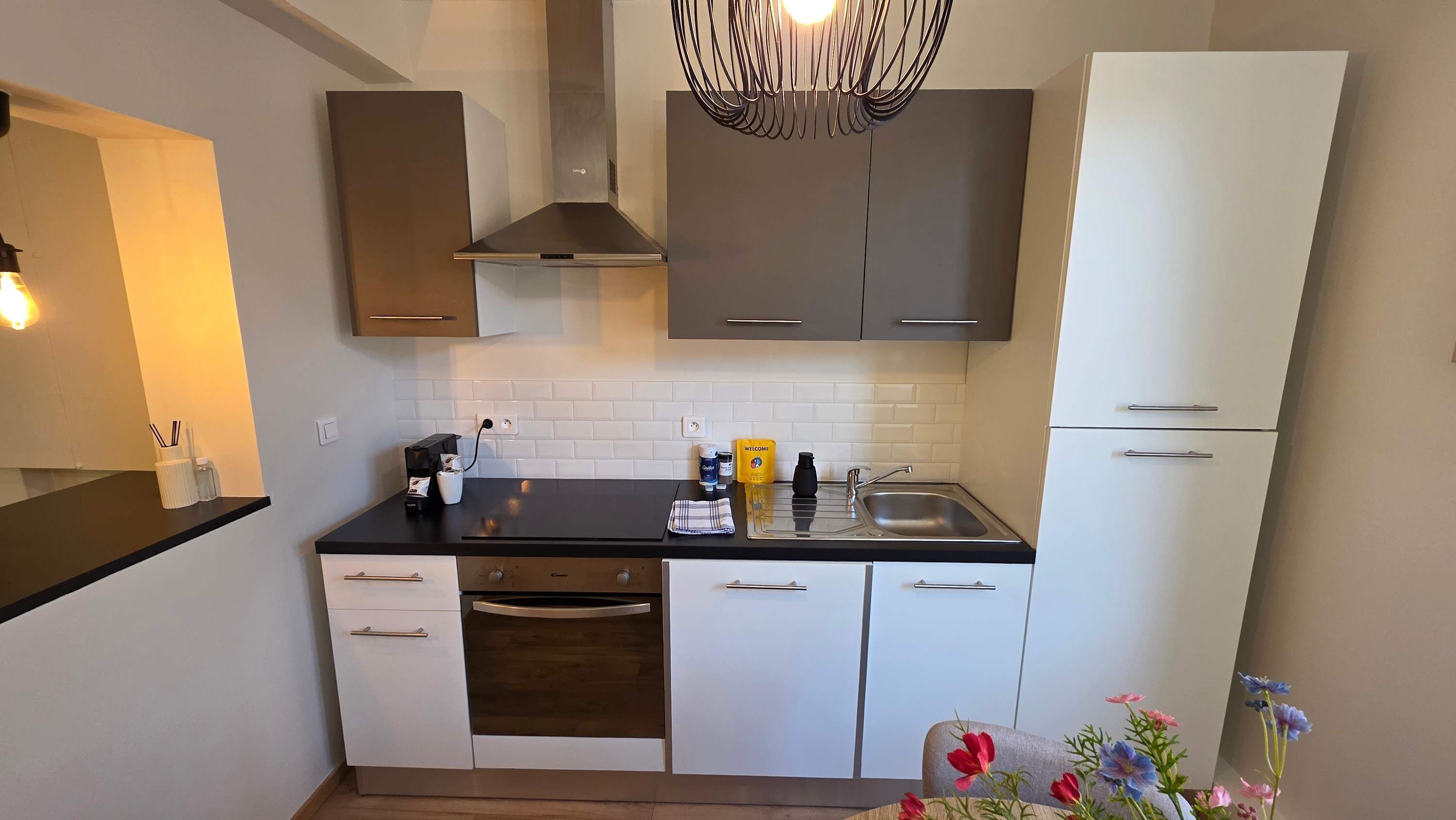 Een moderne keuken met een zwart aanrecht, witte kastjes, een roestvrijstalen spoelbak en een ingebouwde oven.