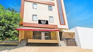 Um hotel moderno com uma placa, uma escadaria e um toldo vermelho.