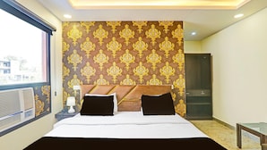 Quarto de hotel com uma cama grande, mesa de cabeceira com abajur, guarda-roupa e janela com vista.