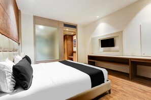 A hotel room with a bed, a TV, a desk, and a wardrobe. - Saver Doublekey Rooms (New Delhi)