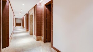 A long, narrow hallway with wooden doors on both sides, leading to multiple rooms. - Saver Doublekey Rooms (New Delhi)