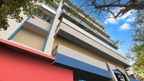 A multi-story building with balconies, a red lower section, and a clear blue sky. - Deluxe Blue Moon Guest House (Kolkata)