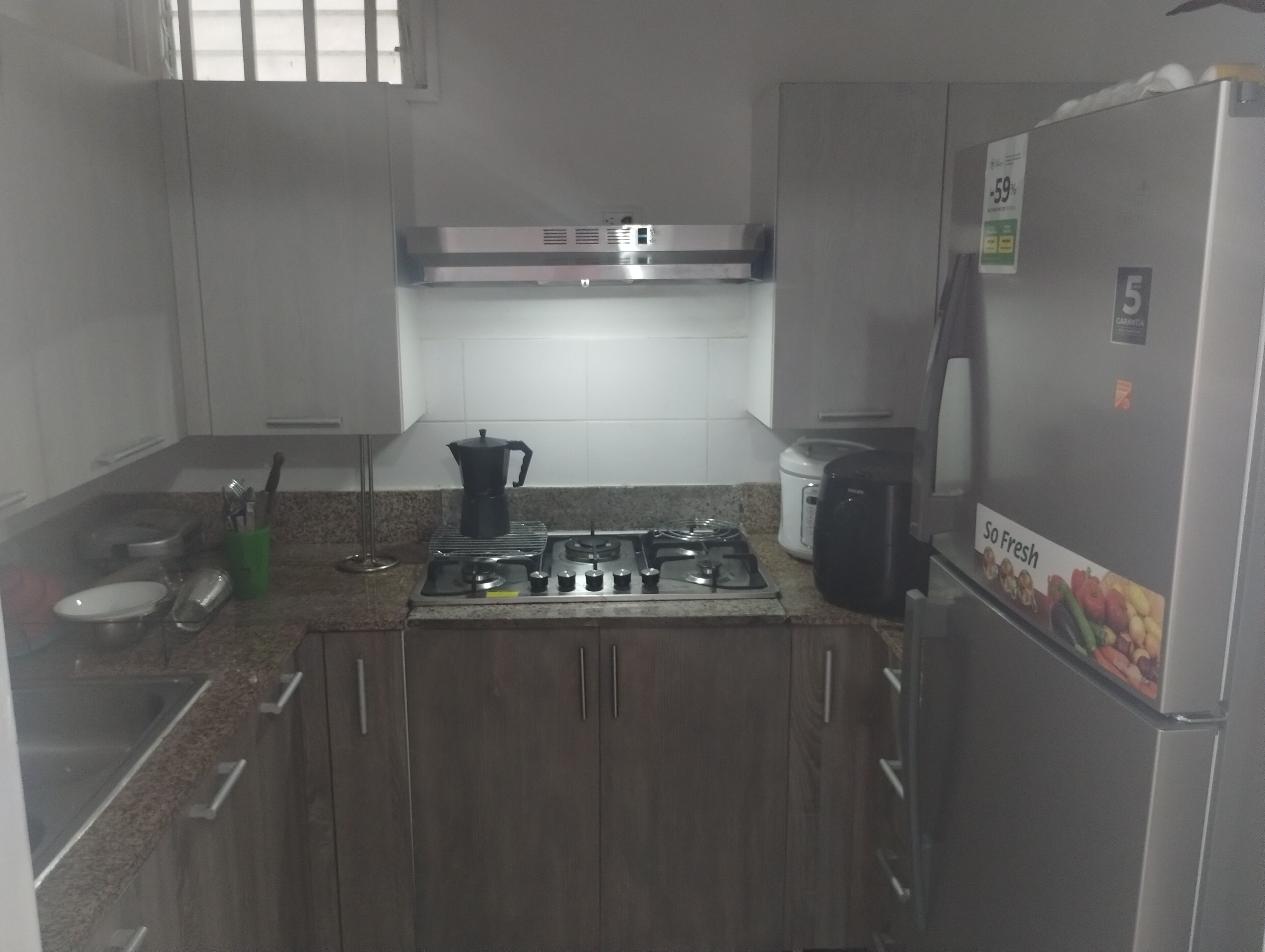 Een kleine keuken met een gasfornuis, een koffiezetapparaat en een koelkast.
