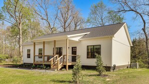 A single-story house with a covered porch, a small front yard, and a clear sky.