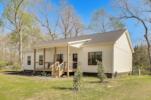 A single-story house with a covered porch, a small front yard, and a clear sky.