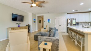 A modern living room with a sofa, a coffee table, a television, and a ceiling fan. - Nature, Disney & More! Family Home in Groveland (Clermont)