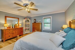 A bedroom with a bed, dresser, wardrobe, and ceiling fan.