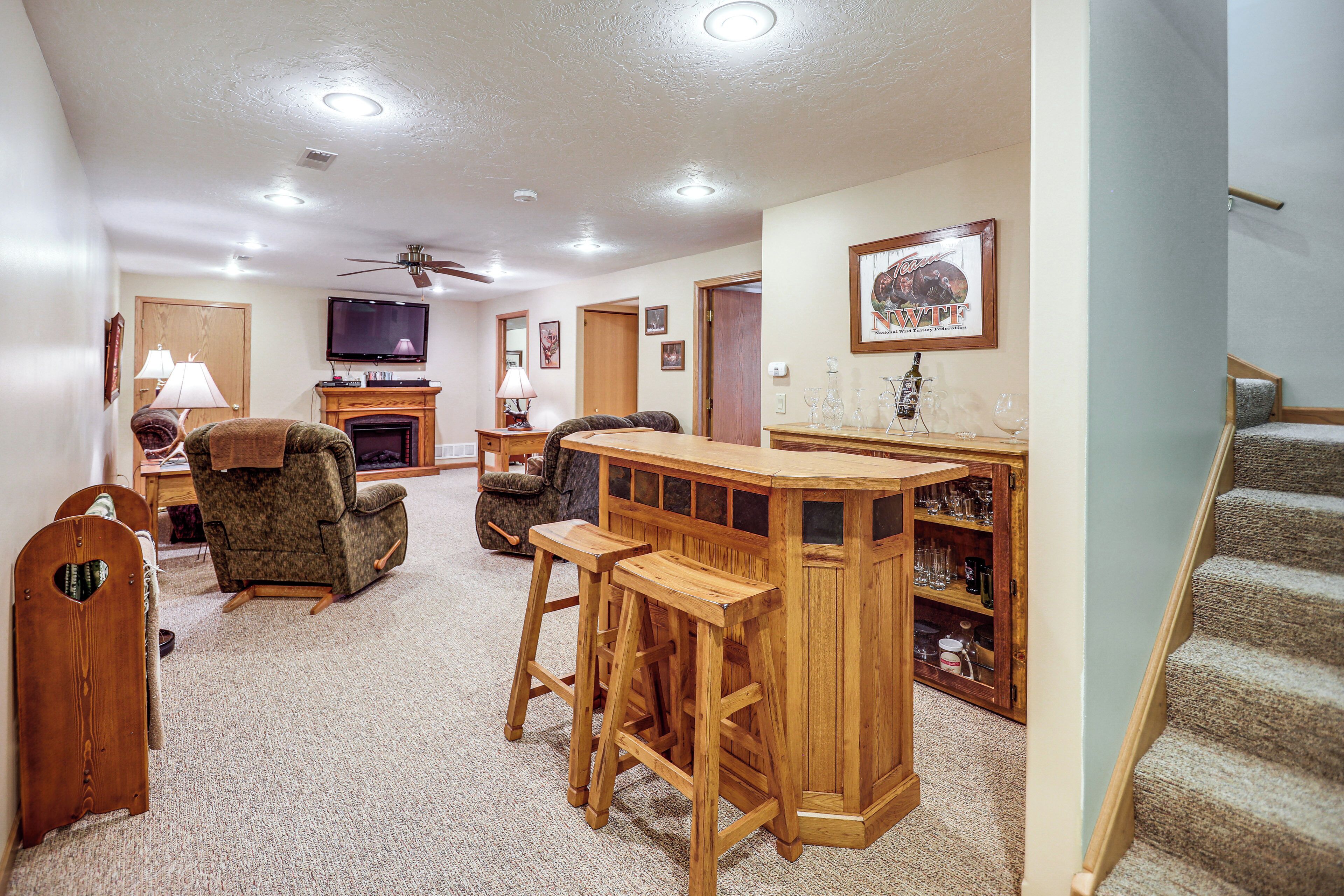 A living room with a fireplace, a TV, and a bar area with stools.