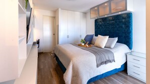 Um quarto com cama, mesa de cabeceira, guarda-roupa e armário embutido.