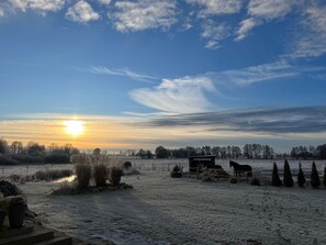 Ländliche Landschaft bei Sonnenuntergang, mit einem Pferd und einer Scheune.