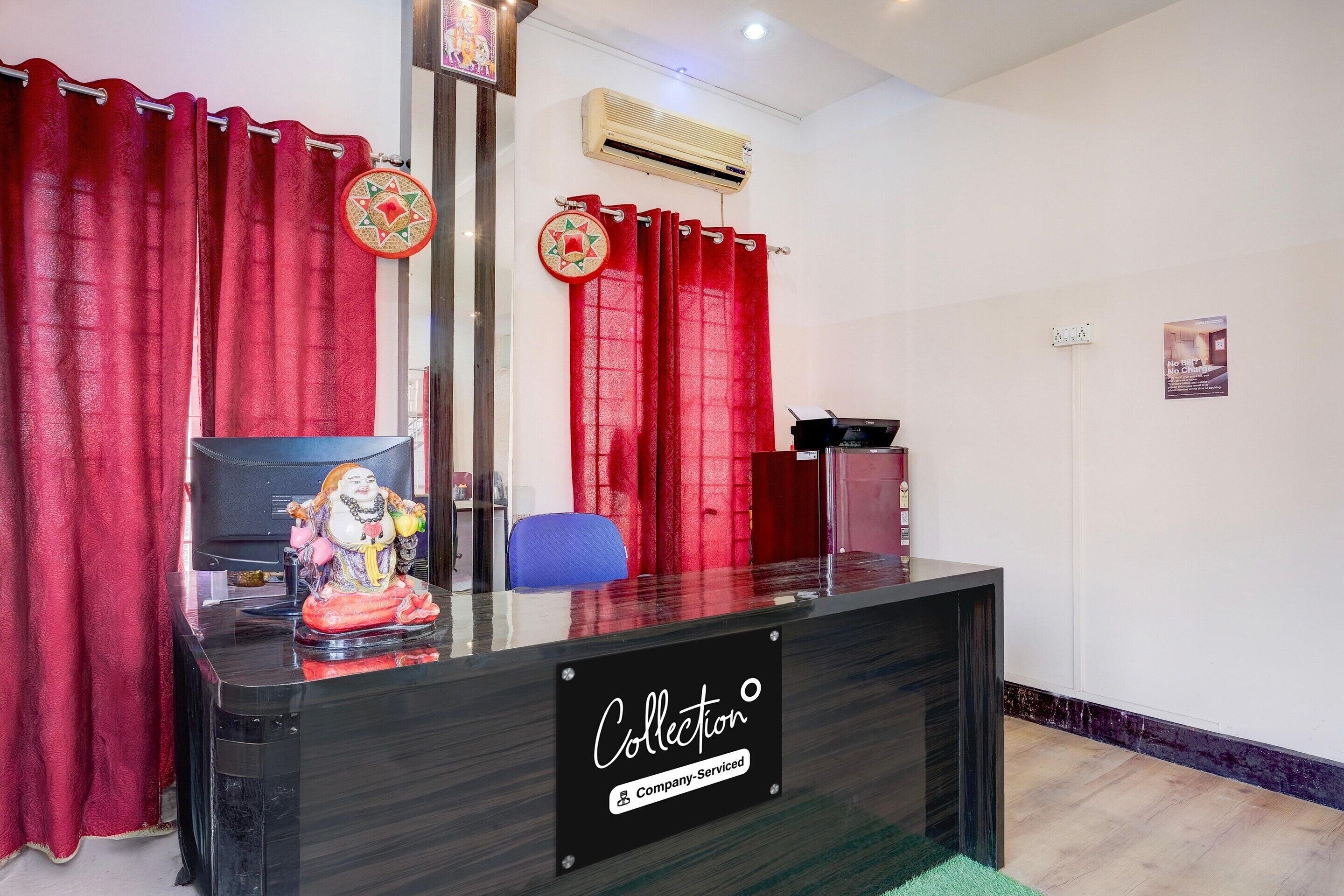 Un mostrador de recepción con un cartel que dice 'Collection Company-Serviced', cortinas rojas, una silla azul y un aire acondicionado montado en la pared.