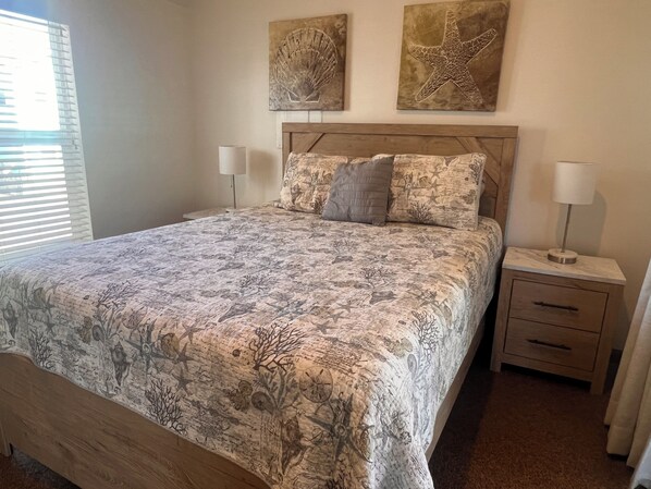 Een slaapkamer met een bed, twee nachtkastjes, een houten hoofdbord en twee aan de muur bevestigde sterfish kunstwerken.