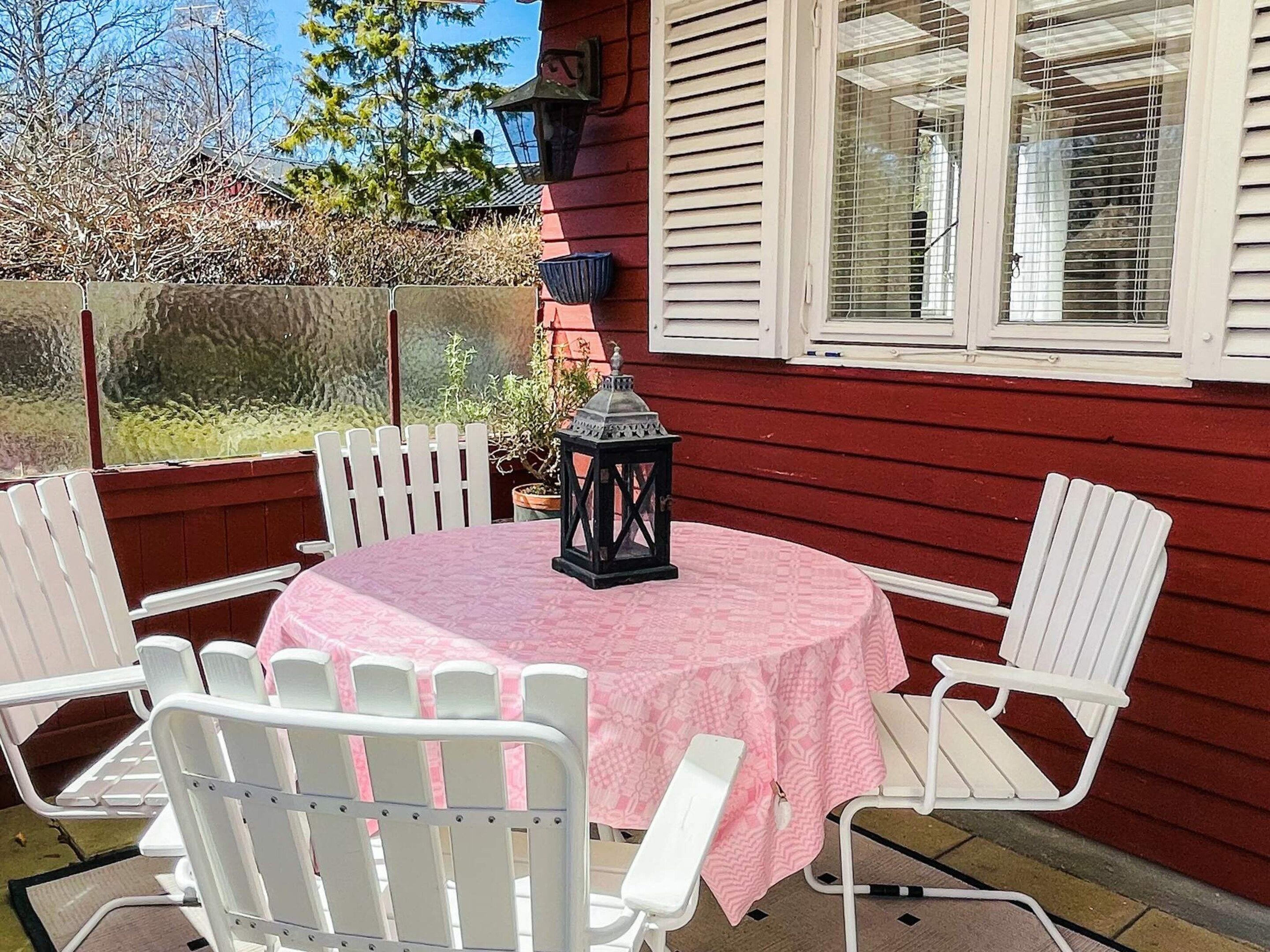 A patio with a round table, white chairs, and a lantern.