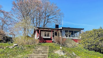 Uma casa com fachada vermelha, uma chaminé visível e um conjunto de degraus de pedra que levam à entrada.