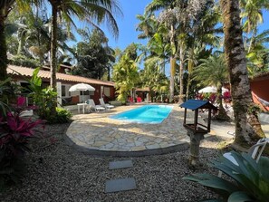 Une piscine entourée de palmiers et bordée d’une terrasse en pierre.