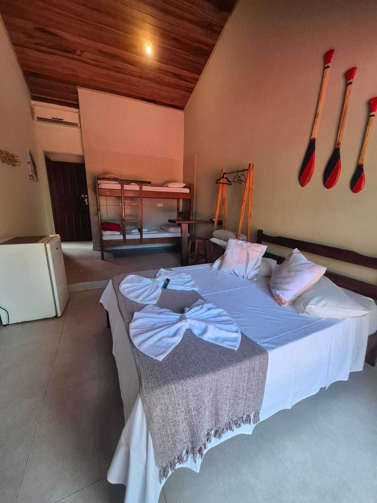 A room with a bed, bunk beds, a small table, and a wall-mounted rack with paddles.