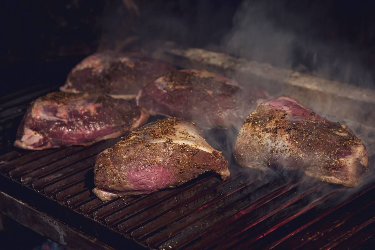 Steaks being grilled on a barbecue.
