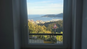 Janela com vista para um horizonte costeiro, um sinal de trânsito e um mural de avisos.