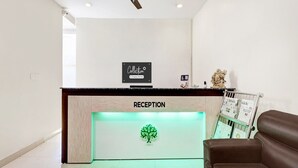 Uma área de recepção com um ventilador de teto, um balcão de atendimento identificado como 'RECEPTION' e uma poltrona de couro marrom.