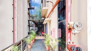 Um corredor com plantas em vasos, um extintor de incêndio e uma escadaria.