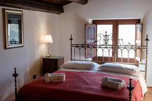 Ein Schlafzimmer mit Bett, Nachttisch, Lampe und einem Fenster mit Blick.