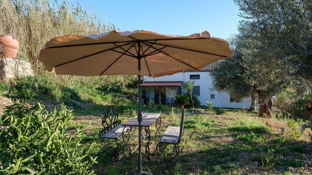 An outdoor seating area with a table and chairs, an umbrella, and a house in the background. - Jupiter's Dreams House With Private Pool (Syracuse)
