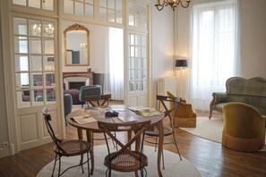A room with a round table, chairs, a mirror, a fireplace, and a sofa. - Gîte Saint Sauveur en Puisyae (Leugny)